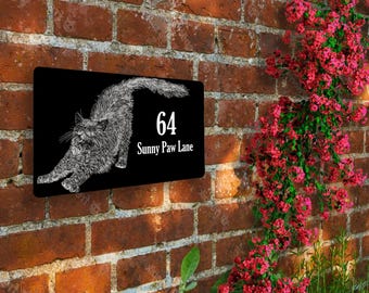 May include: Black house number sign with a white silhouette of a cat stretching. The sign reads "64 Sunny Paw Lane".