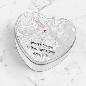 May include: A heart-shaped metal tin featuring a grayscale map of Boston, Massachusetts. A small red heart icon marks a location on the map. The text reads James & Georgia, 10 Year Anniversary, and the date 28/02/2026 in black script and print.