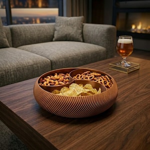 Könnte beinhalten: Eine hölzerne Servierschale mit drei Fächern, gefüllt mit Nüssen, Brezeln und Chips. Die Schale steht auf einem dunklen Holztisch, im Hintergrund ein Glas Bier und ein Sofa. Die Schale hat eine geriffelte Außenseite.
