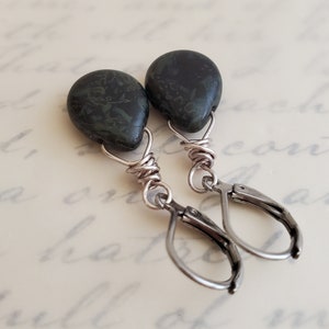 May include: A pair of dangle earrings with dark green stone teardrop shaped beads and silver wire wrapped hoops.