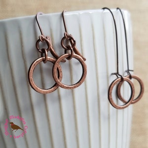 Könnte beinhalten: Zwei Paar Kupfer-Hoop-Ohrringe. Das größere Paar hat ein Doppelring-Design. Das kleinere Paar hat ein Einzelring-Design.