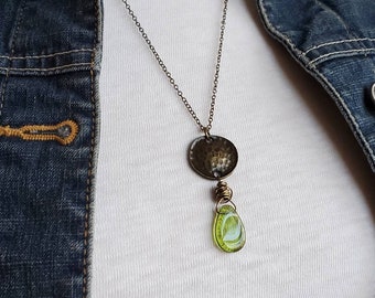 May include: A silver chain necklace with a hammered silver pendant and a green glass teardrop pendant.