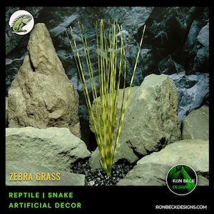 May include: Artificial zebra grass plant for reptile or snake enclosures. The plant is green and yellow with long, thin blades. It is displayed on a bed of black gravel with rocks.