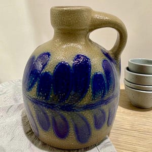 May include: A set of three ceramic mugs with a speckled, matte finish. The mugs are in shades of cream, light gray, and dark gray. Each mug has a simple, minimalist design, perfect for coffee or tea.