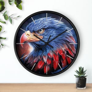 Pode incluir: Relógio de parede redondo preto com uma ilustração detalhada da cabeça de uma águia. A águia tem penas azuis, um bico vermelho e detalhes vermelhos no peito. Os ponteiros do relógio são pretos e o fundo é azul escuro.