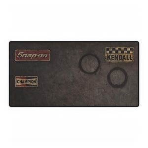 May include: A rectangular, dark gray mousepad with a distressed texture. It features three vintage-style logo patches: "Snap-on" in red, "Champion" in white, and "Kendall" with a checkered background. Two dark ring stains are visible.
