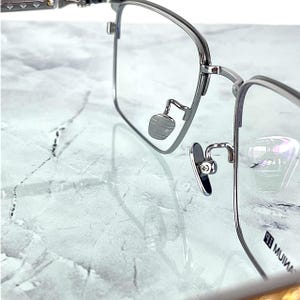 Titanium rectangular eyeglass frames in black and silver with golden temple accents. Suitable for prescription or fashion lenses. Includes hard ETE case, soft pouch, and cleaning cloth. Lightweight, durable, and hypoallergenic design for men and women. Ideal as a stylish gift with fast worldwide shipping.