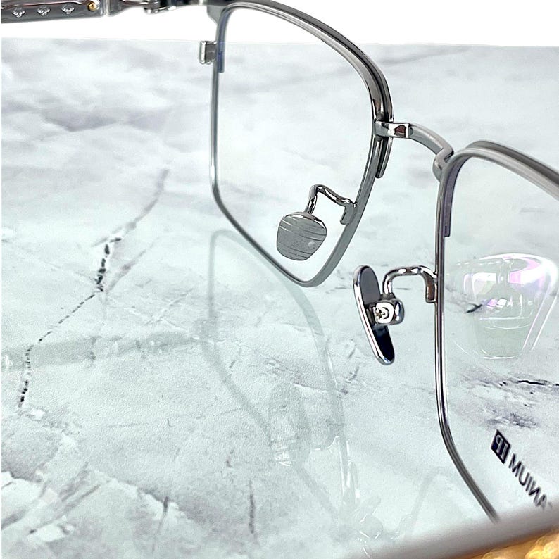 Titanium rectangular eyeglass frames in black and silver with golden temple accents. Suitable for prescription or fashion lenses. Includes hard ETE case, soft pouch, and cleaning cloth. Lightweight, durable, and hypoallergenic design for men and women. Ideal as a stylish gift with fast worldwide shipping.