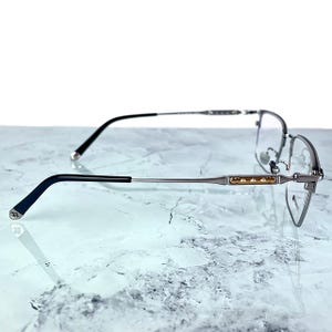Titanium rectangular eyeglass frames in black and silver with golden temple accents. Suitable for prescription or fashion lenses. Includes hard ETE case, soft pouch, and cleaning cloth. Lightweight, durable, and hypoallergenic design for men and women. Ideal as a stylish gift with fast worldwide shipping.