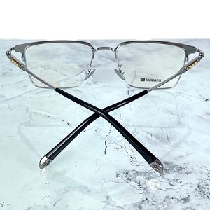 Titanium rectangular eyeglass frames in black and silver with golden temple accents. Suitable for prescription or fashion lenses. Includes hard ETE case, soft pouch, and cleaning cloth. Lightweight, durable, and hypoallergenic design for men and women. Ideal as a stylish gift with fast worldwide shipping.