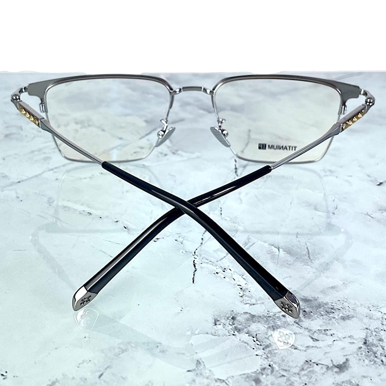 Titanium rectangular eyeglass frames in black and silver with golden temple accents. Suitable for prescription or fashion lenses. Includes hard ETE case, soft pouch, and cleaning cloth. Lightweight, durable, and hypoallergenic design for men and women. Ideal as a stylish gift with fast worldwide shipping.