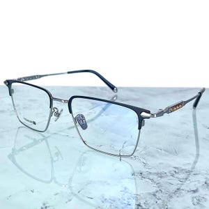 Titanium rectangular eyeglass frames in black and silver with golden temple accents. Suitable for prescription or fashion lenses. Includes hard ETE case, soft pouch, and cleaning cloth. Lightweight, durable, and hypoallergenic design for men and women. Ideal as a stylish gift with fast worldwide shipping.