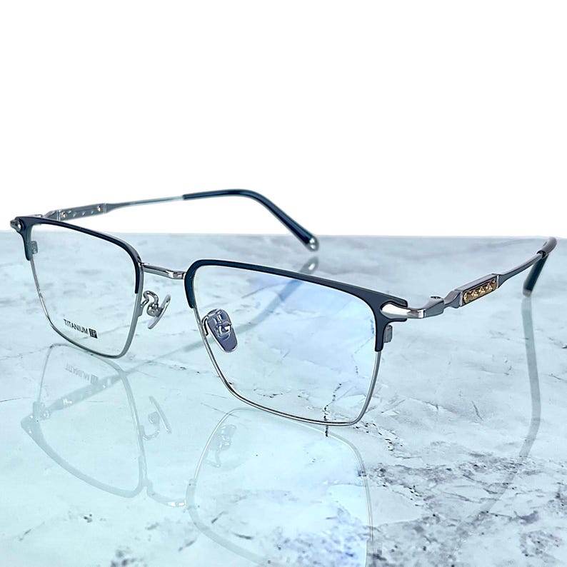 Titanium rectangular eyeglass frames in black and silver with golden temple accents. Suitable for prescription or fashion lenses. Includes hard ETE case, soft pouch, and cleaning cloth. Lightweight, durable, and hypoallergenic design for men and women. Ideal as a stylish gift with fast worldwide shipping.