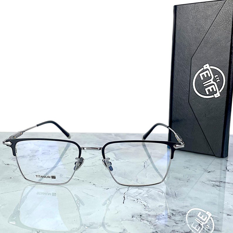 Titanium rectangular eyeglass frames in black and silver with golden temple accents. Suitable for prescription or fashion lenses. Includes hard ETE case, soft pouch, and cleaning cloth. Lightweight, durable, and hypoallergenic design for men and women. Ideal as a stylish gift with fast worldwide shipping.