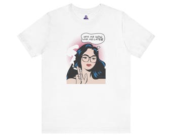 Könnte beinhalten: Weißes T-Shirt mit einer Pop-Art-Illustration einer Frau mit dunklem Haar und Brille. Das Bild enthält eine Sprechblase mit dem Text "Hate Me Now, Love Me Later."