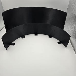 May include: Two black, curved, 3D-printed plastic pieces. The larger piece is a solid arc, while the smaller piece has supporting tabs along its base. The pieces are set against a white background.