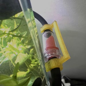 May include: A yellow 3D printed aquarium filter attachment with a clear tube and a red filter inside. The filter is attached to a black hose.