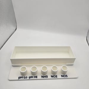 May include: A white plastic tray with a rectangular container and a base with five small cylindrical containers. The base is labeled with the text "pH Lo pH Hi NH3 NO2 NO3".