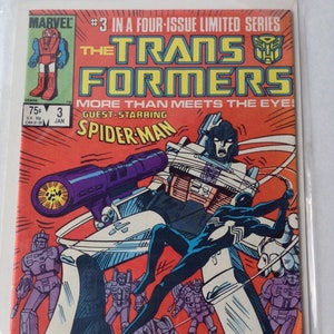 May include: Comic book cover for The Transformers #3, featuring guest star Spider-Man. The cover art shows a battle scene with robots and Spider-Man in action against a red background. The Marvel and Transformers logos are visible.