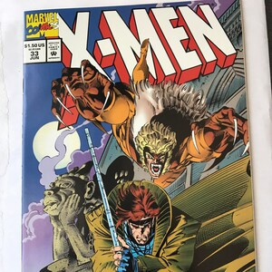 May include: A Marvel Comics X-Men issue 33 comic book featuring Sabretooth leaping with claws extended above Gambit, who holds a glowing staff. The cover includes the title X-Men, the price of $1.50 US, and a stone gargoyle figure in the background.