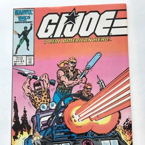 May include: A G.I. Joe comic book cover with dynamic illustrations. The title "G.I. Joe" is prominently displayed, along with the slogan "A Real American Hero!" and a group of armed characters in a vehicle. The Marvel 25th Anniversary logo is also visible.