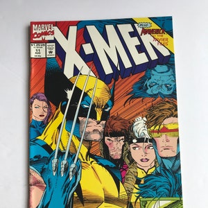 Puede incluir: Una portada de cómic vintage de X-Men con Wolverine con las garras extendidas, con un traje amarillo y azul. También aparecen otros personajes. El cómic es de Marvel Comics, con el texto "X-MEN" en un lugar destacado.