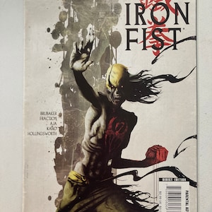 Puede incluir: Portada de cómic con un personaje con una máscara amarilla y cabello negro, con el título "The Immortal Iron Fist" en letras grandes y negritas.