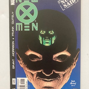 May include: A comic book cover for "New X-Men" features a stylized illustration of a face with a dark background and the text "New X-Men" in green and white. The cover includes the Marvel logo and the words "Nuff Said".