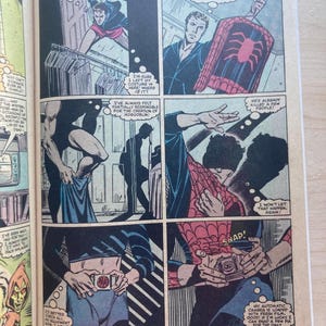 May include: A comic book page featuring six panels depicting a person putting on a red and blue spider-themed costume. The panels show the character retrieving the suit from a closet, adjusting a belt with a spider emblem, and loading a camera.
