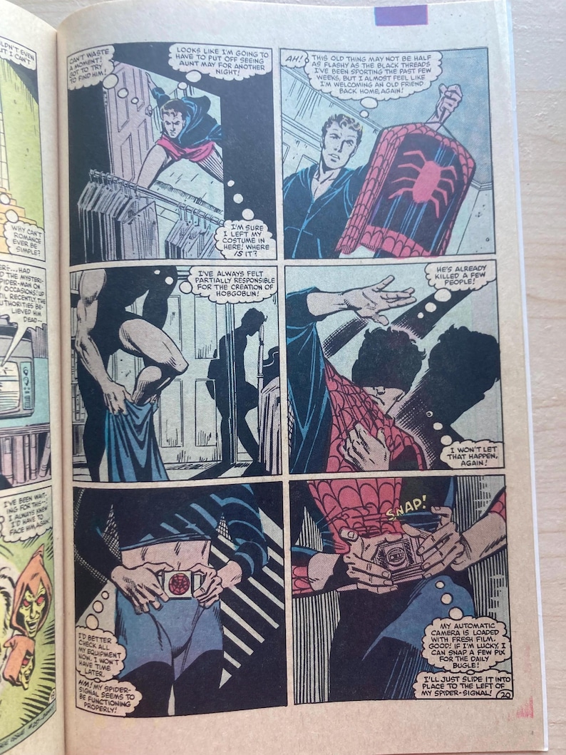 May include: A comic book page featuring six panels depicting a person putting on a red and blue spider-themed costume. The panels show the character retrieving the suit from a closet, adjusting a belt with a spider emblem, and loading a camera.