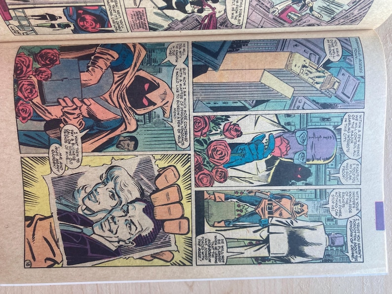 May include: A vintage comic book page featuring multiple panels with illustrations of a hooded figure in a tan cloak, a man in a suit, and a woman. The artwork includes red roses, speech bubbles with text, and a photograph held by a hand.
