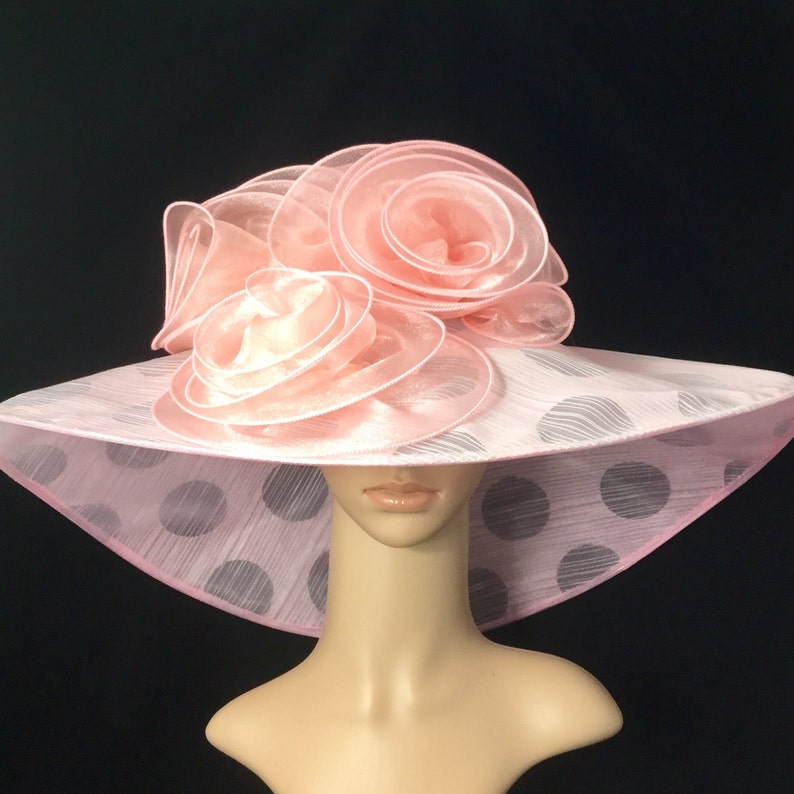 May include: A pink and white polka dot hat with a large pink flower on top.