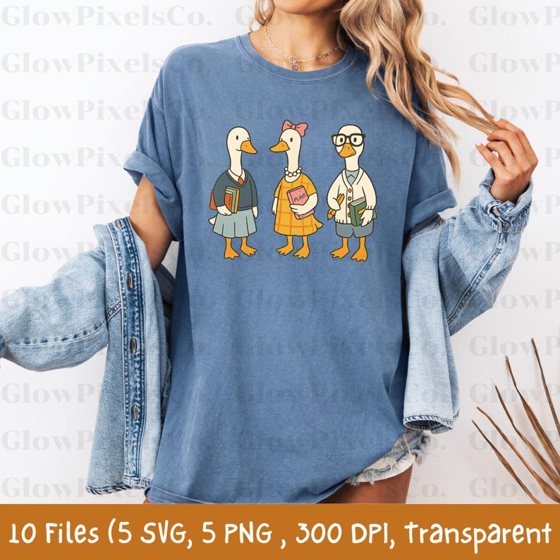 K&ouml;nnte beinhalten: Blaues T-Shirt mit einer Cartoon-Illustration von drei G&auml;nsen in Schulkleidung, die jeweils B&uuml;cher halten. Die G&auml;nse tragen verschiedene Outfits, darunter einen Rock, ein Kleid und einen Pullover. Der Text unten lautet "10 Files (5 SVG, 5 PNG, 300 DPI, transparent".