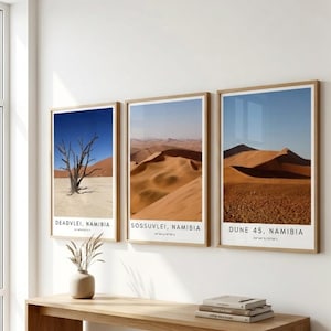Peut inclure: Trois impressions encadrées de paysages désertiques de Namibie. Chaque impression a un cadre en bois et un bord blanc. Les impressions présentent des images de dunes de sable, d'un arbre mort et le texte "DEADVLEI, NAMIBIA", "SOSSUSVLEI, NAMIBIA", et "DUNE 45, NAMIBIA".