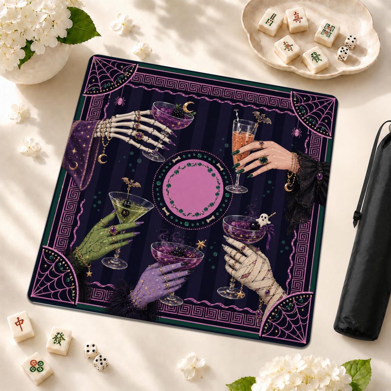 May include: A square mat featuring a dark purple and black striped background with a central pink circle. Four hands, including a skeleton hand, a green hand, a purple hand, and a bandaged hand, hold cocktail glasses. The border has spiderwebs.