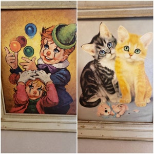 May include: Two framed vintage paintings. One depicts a clown juggling colorful balls, with another clown looking distressed. The second painting shows two kittens, one gray tabby and one orange, with a small stuffed animal.