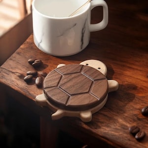 Puede incluir: Un posavasos de madera con forma de tortuga con un acabado de nogal marrón oscuro. El posavasos está hecho de dos piezas de madera, con la pieza superior siendo una forma de caparazón ligeramente elevada.