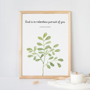 Puede incluir: Una impresión enmarcada con fondo blanco y una ilustración de acuarela de una rama verde con hojas. El texto "God is in relentless pursuit of you" está impreso en negro en la parte superior de la impresión. El texto "Patrick Kearon" está impreso en negro debajo de la cita.