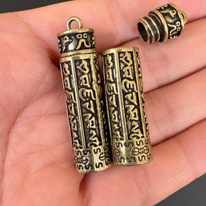 Peut inclure: Gros plan sur trois récipients cylindriques en laiton antique avec des motifs gravés complexes. Un récipient est ouvert, révélant son intérieur. Les récipients ont une apparence vieillie et ternie, suggérant qu'il s'agit d'objets vintage ou antiques.