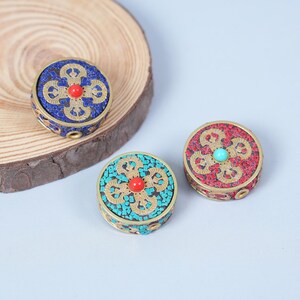 K&ouml;nnte beinhalten: Drei runde, dekorative Boxen mit aufwendigen Designs. Eine Box ist blau mit goldenen Akzenten, eine weitere t&uuml;rkis und die dritte rot. Jede hat einen zentralen Stein und ein detailliertes Muster.