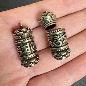 Puede incluir: Una taza de cerámica blanca con un asa negra y el texto "But First, Coffee" en negrita negra. La taza se encuentra sobre un fondo borroso, sugiriendo un ambiente acogedor.