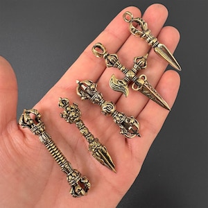 Puede incluir: Cinco dagas de bronce de estilo antiguo con diseños intrincados. Cada daga presenta un mango y una forma de hoja únicos, con detalles que incluyen coronas y espirales. Las dagas se exhiben sobre un fondo oscuro.