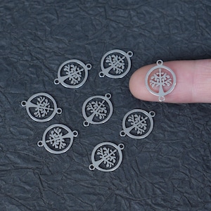 May include: Seven silver-toned metal charms, each featuring a circular frame containing a cutout tree of life design. Each charm has two small loops on opposite sides for attachment, with one charm being held to show its scale and circular shape.