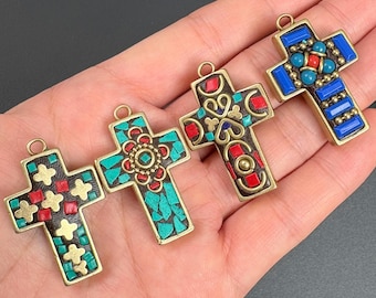 Könnte beinhalten: Vier dekorative Kreuze mit aufwendigen Designs. Jedes Kreuz hat einen goldfarbenen Rahmen und ist mit farbigen Einlegearbeiten in Rot, Blau und Türkis verziert. Die Kreuze haben oben eine Schlaufe zum Aufhängen.