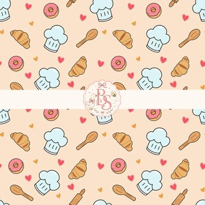 Può includere: Un motivo ripetuto su sfondo color pesca chiaro con cappelli da chef azzurri, cucchiai di legno marroni, ciambelle glassate rosa, croissant dorati e piccoli cuori rossi e arancioni. Un logo circolare centrale mostra le lettere BS.