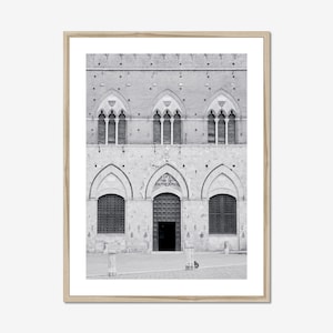 May include: Black and white framed print of a historic building facade. The building features arched windows and a central doorway. The architectural style is reminiscent of Gothic or Romanesque design, with a textured stone exterior.