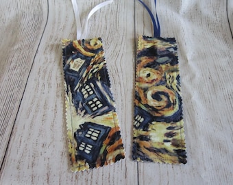 May include: Two fabric bookmarks with a yellow and blue Starry Night design. One bookmark has a white ribbon and the other has a blue ribbon.