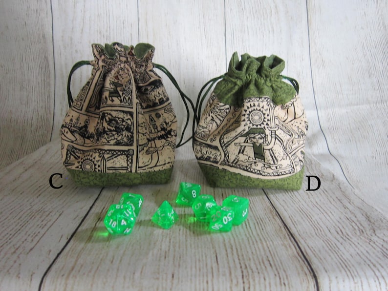 May include: Two green drawstring bags with a beige fabric featuring a black and white print. The bags are labeled "C" and "D". Green dice are scattered in front of the bags.