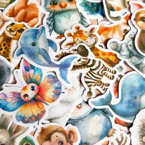 K&ouml;nnte beinhalten: Eine Sammlung farbenfroher Tieraufkleber im Aquarellstil. Die Aufkleber zeigen verschiedene Tiere, darunter eine Eule, ein Delfin, ein Schmetterling, ein Zebra und ein Wal. Die Aufkleber sind detailliert mit leuchtenden Farben und niedlichen Ausdr&uuml;cken.