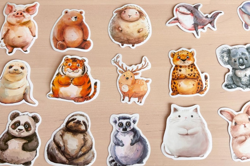 K&ouml;nnte beinhalten: Eine Sammlung von Aquarell-Tieraufklebern, darunter ein Schwein, ein B&auml;r, ein Schaf, ein Hai, eine Robbe, ein Tiger, ein Hirsch, ein Leopard, ein Koala, ein Panda, ein Faultier, ein Lemur, eine Katze und ein Kaninchen. Jeder Aufkleber hat einen wei&szlig;en Rand.
